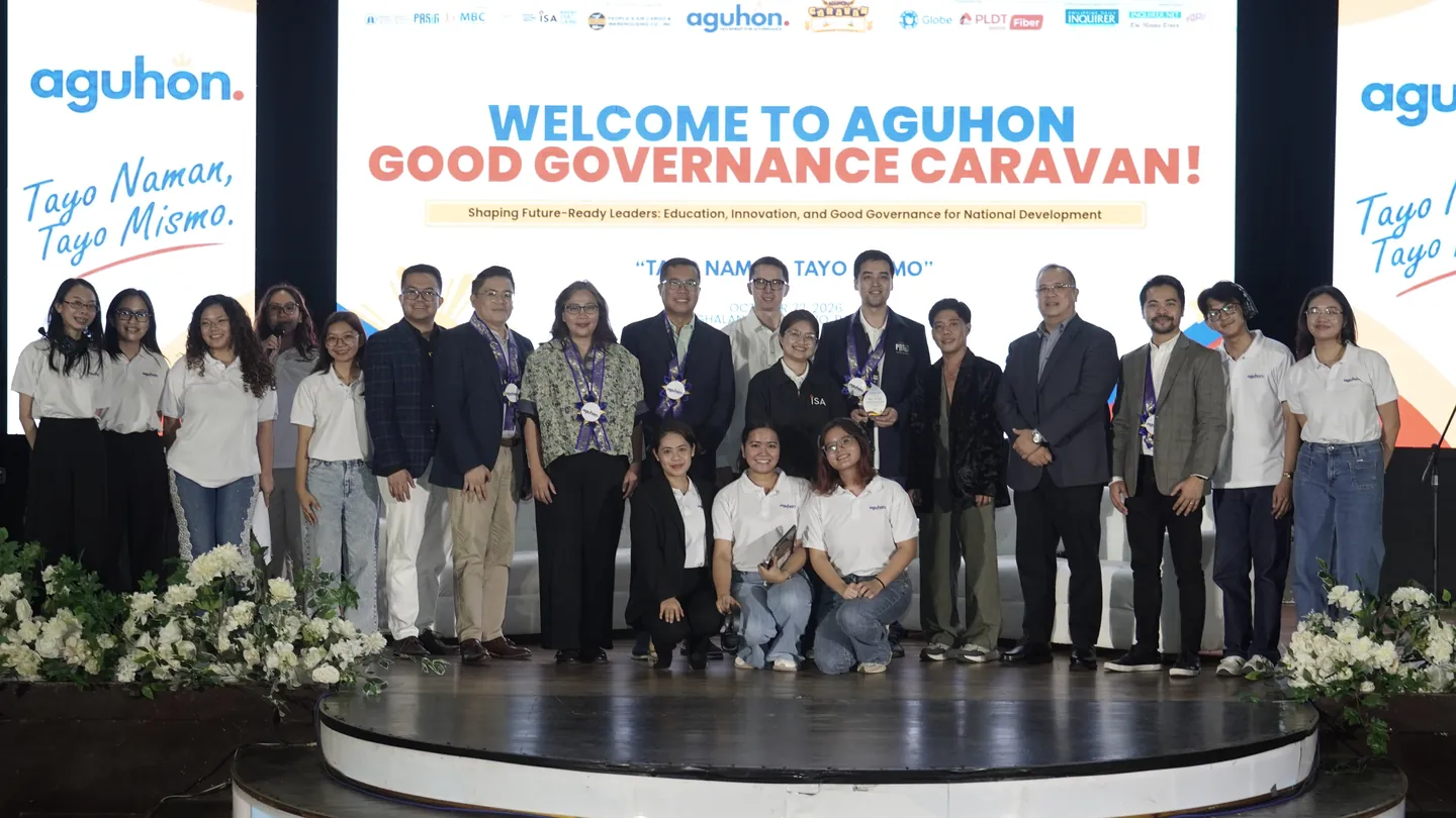 Speakers and Aguhon Movement for Governance organizers pose for a group photo on stage, under screens reading “Welcome to Aguhon Good Governance Caravan” and “Tayo Naman, Tayo Mismo”